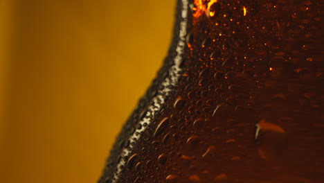 Macro-Shot-Of-Condensation-Droplets-On-Revolving-Bottle-Of-Cold-Beer-Or-Soft-Drinks-Against-Yellow-Background-2